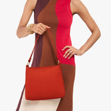 Paprika Small | Model holding a triangular shoulder bag with antiqued brass finished 
