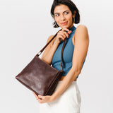 Coldbrew Classic | Model holding triangular shoulder bag with antiqued brass finished hardware