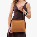 Desert Flower | Model holding a triangular shoulder bag with antiqued brass finished 