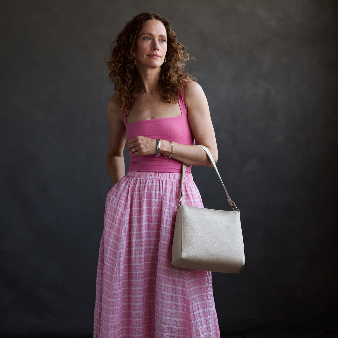 Jasmine | Model holding a triangular shoulder bag with antiqued brass finished 