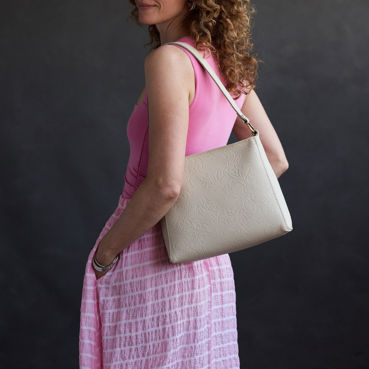 Jasmine | Model holding a triangular shoulder bag with antiqued brass finished 