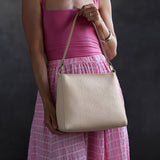 Jasmine | Model holding a triangular shoulder bag with antiqued brass finished 