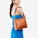 Sienna Small | Model holding triangular shoulder bag with antiqued brass finished hardware