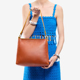 Sienna Small | Model holding triangular shoulder bag with antiqued brass finished hardware