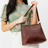 Cognac Small | Model holding triangular shoulder bag with antiqued brass finished hardware