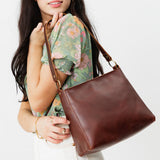 Cognac Small | Model carrying triangular shoulder bag with antiqued brass finished hardware