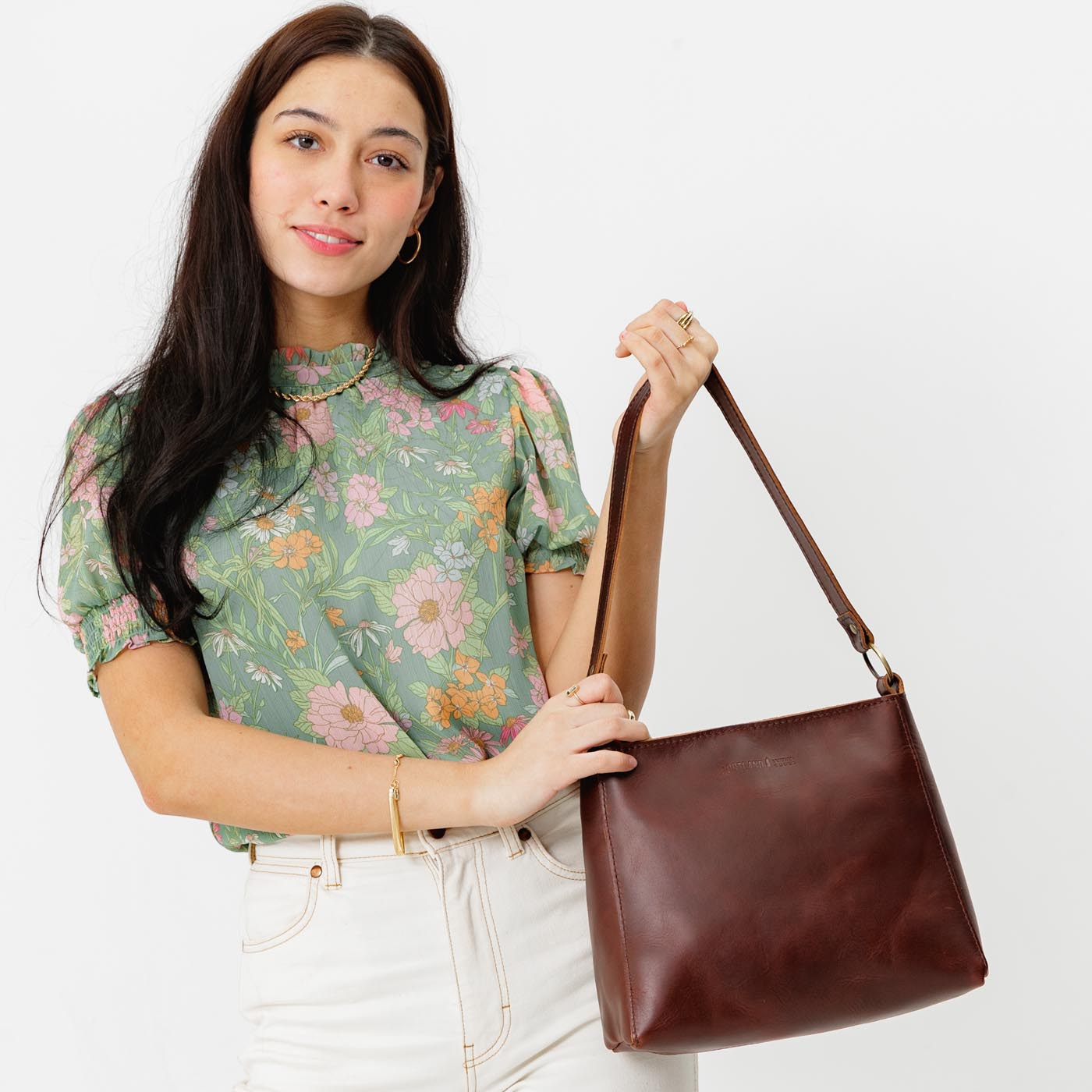 Cognac*Small | Model holding triangular shoulder bag with antiqued brass finished hardware